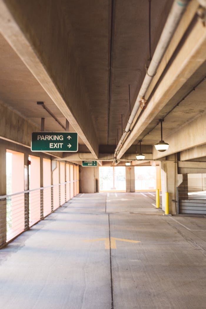 services-04 A well-lit, vacant parking garage with overhead signage and concrete structure.