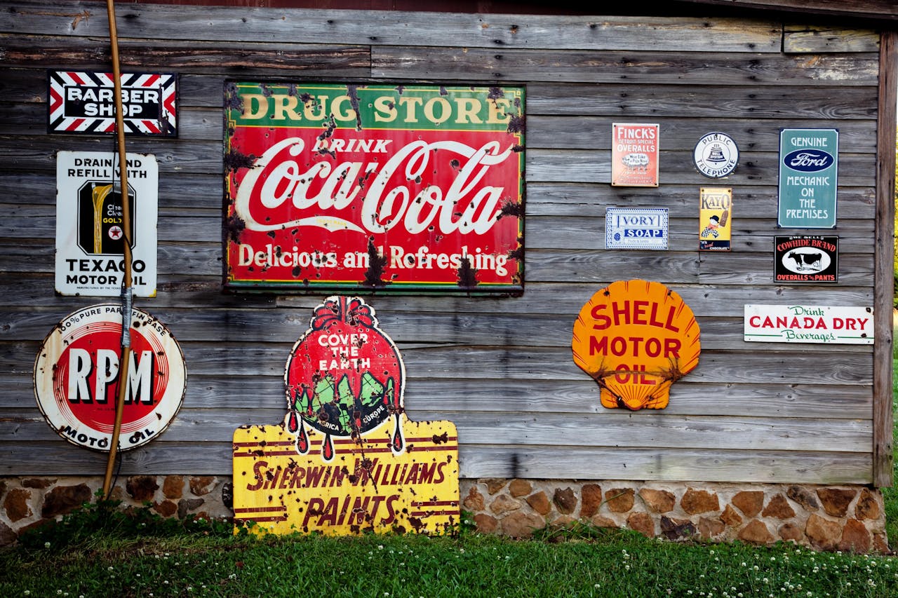 why-choose-me Collection of vintage advertising signs on rustic wooden wall showcasing classic brands.