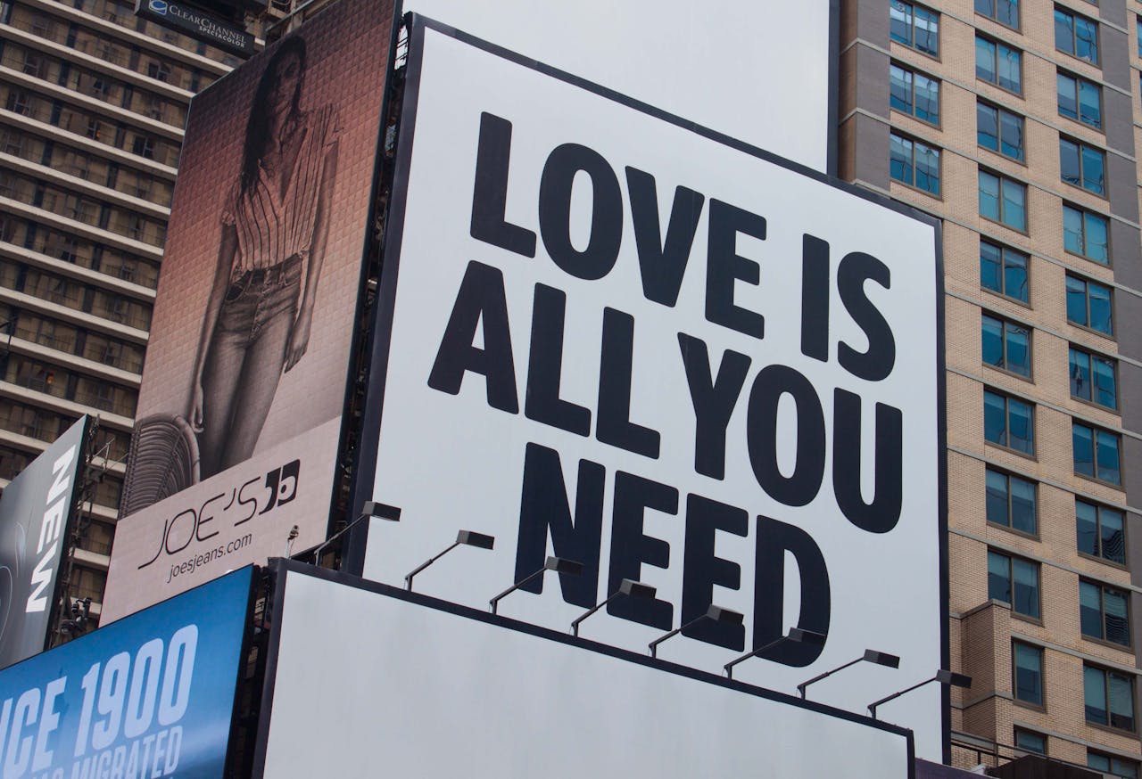 service-03 Large city billboard reads 'Love Is All You Need' in New York City street.