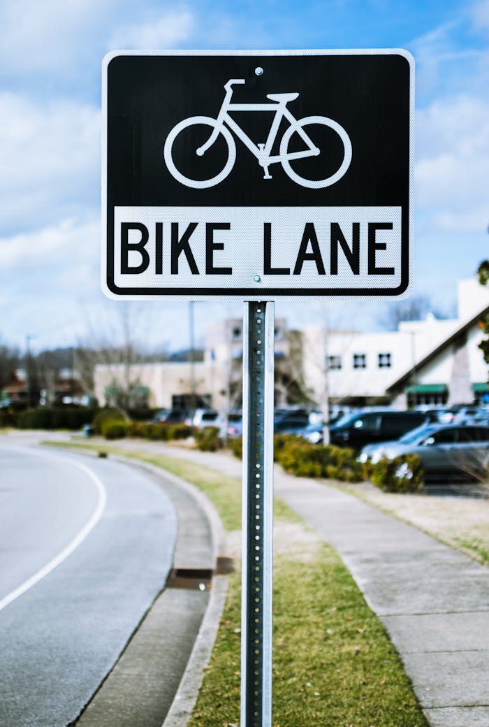 about-me Close-up of a bike lane sign by the road with clear blue skies in an urban setting.